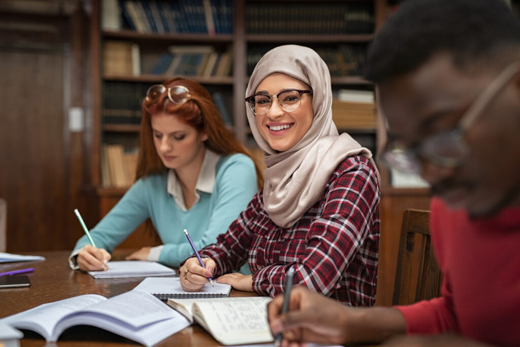 Three adult students working through coursework together at a library table